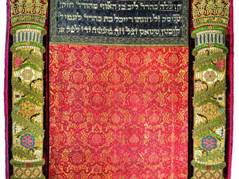 Torah Curtain from Prague Embroidered curtain of columns with crowns on left and right sides and decorative floral motifs throughout, and Hebrew text in top center.