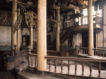 Photograph of room with raised central platform with columns and several chandeliers.