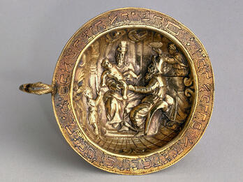 Plate engraved with Hebrew letters around rim and image of man holding child on a chair.