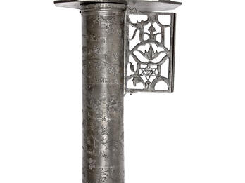 Emblem of the Jewish Butchers’ Guild Metal cylindrical object with carving of lion holding axe on top, and decorative carving on bottom.