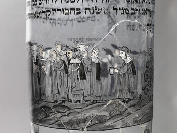 Glass for a Burial Society’s Annual Banquet Glass cup etched with Hebrew text and image of group of people walking.