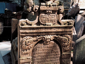 Tombstone of Hendl bat Eberl Geronim Tomb with high tombstones on either end, lions, shield and floral decorations on top, and Hebrew inscription on surface of stone.