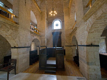 Velika Avlija (Old Synagogue), Sarajevo Photograph of room with arched stone doorways and central wooden platform.