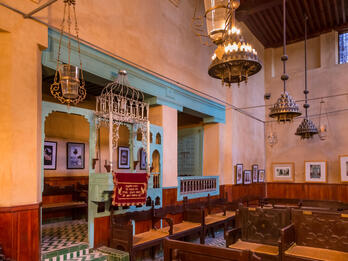 Ibn Danan Synagogue, Fez, Morocco Photograph of room with nook and podium on one side and wooden benches in middle of room.
