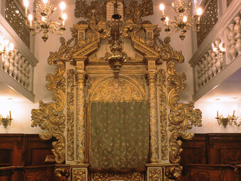 Italian Synagogue, Conegliano Veneto, Italy Photograph of room with large carved Torah ark with pews on either side of room and screened second-floor balcony.
