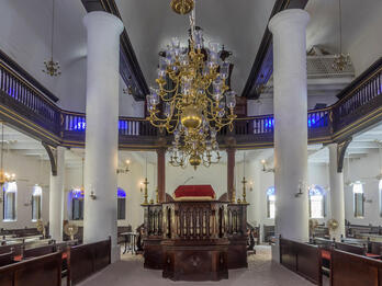 The Mikve Israel-Emanuel Synagogue, Interior Photograph of room with central podium, two-story columns, benches facing podium, and balcony above, with sand floor.