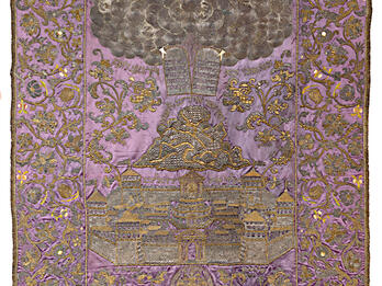 Cloth with embroidered image of tablets in clouds above mountain and city. 