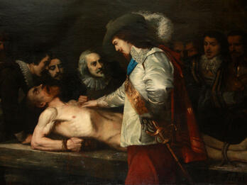 Harvey Demonstrating the Circulation of the Blood to Charles I Painting of well-dressed man in hat with plume and sword putting his hand on the chest of a nude man tied down prone on a table with face upturned and mouth open, as several well-dressed men look on from the far side of the table.