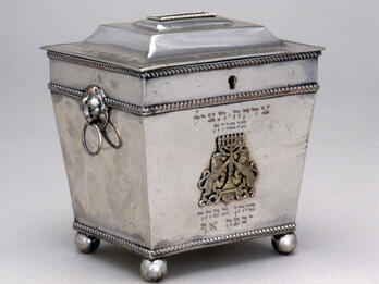 Silver cast and engraved container featuring lions holding menorah.