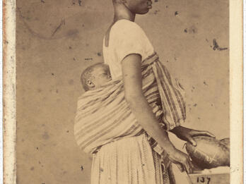 Negersklavin Bahia (Black Slave Bahia) Full body profile photograph of person in profile with baby in shawl on her back.