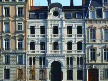 Grand Synagogue of Lyon Photography of street view of buildings with low stone wall in front.