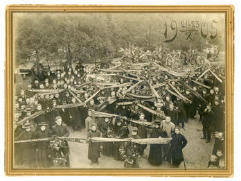 Photograph depicting a crowd of people holding a long ribbon with Russian text on it.