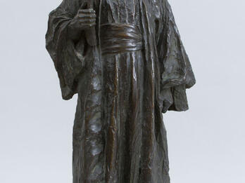 Jewish Scholar Sculpture of a figure in robe and hat, carrying a book.