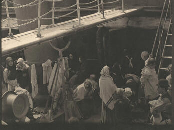 Photograph of a ship deck with two stories filled with people.