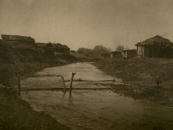Russian Famine Landscape Photograph of landscape with creek lined with small huts.