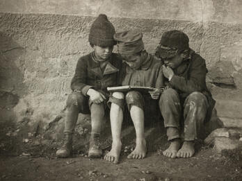 Photograph of three boys looking at a book together.