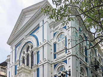 Photograph of building façade with significant decorative trim on window frames and beams.