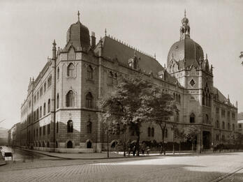 Museum of Applied Arts (facing Üllői Street) Photograph of brick building on street corner with ornate roof finials and domed roofs.