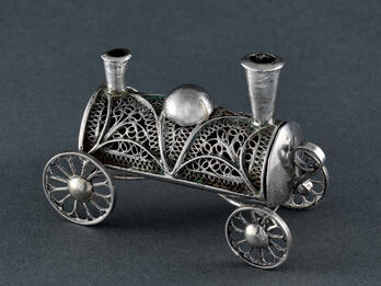 Train-Shaped Besamim Box Filigree container in shape of a train car with four wheels and two smoke stacks.