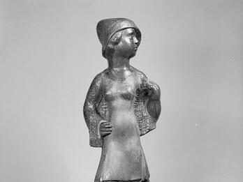 Sculpture of woman wearing dress and hat looking to her left.