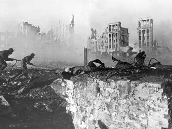 Stalingrad Attack Photograph of soldiers holding guns as they approach ruins of a bombed city.