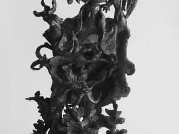 The Prayer Bronze sculpture depicting a standing man, surrounded by harsh foliage and holding a rooster above his head.
