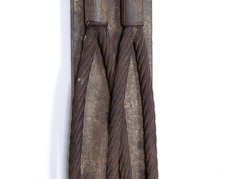Industrial iron sculpture with two curved cords that meet at the top.