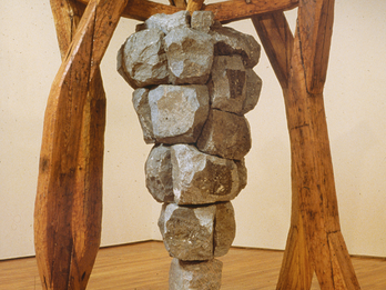 Sculpture of iron grape cluster hanging on wooden framework.