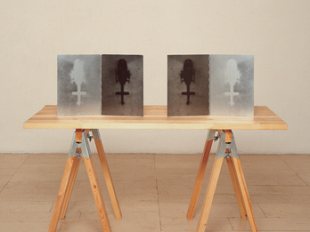 Avodat-Ach Sawhorse table with four images of a helicopter from a bird's-eye view propped up on it.