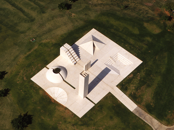 Kikar Levana (White Square) Concrete sculpture featuring a pyramid, water channel, tower with wind flutes, and a dome with olive tree in center set in a field.