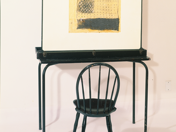 The Empty Chair Sculpture of empty chair at desk that holds up a painting resembling a flag.