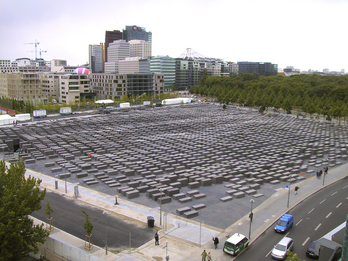 Aerial photograph of many concrete slabs in an empty lot surrounded by buildings. 