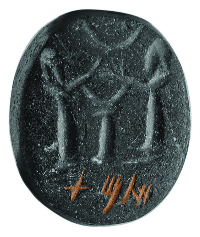 Stone seal with two bearded men with their hands raised flanking an altar or pedestal with crescents above and below their hands, and Hebrew inscription at bottom.