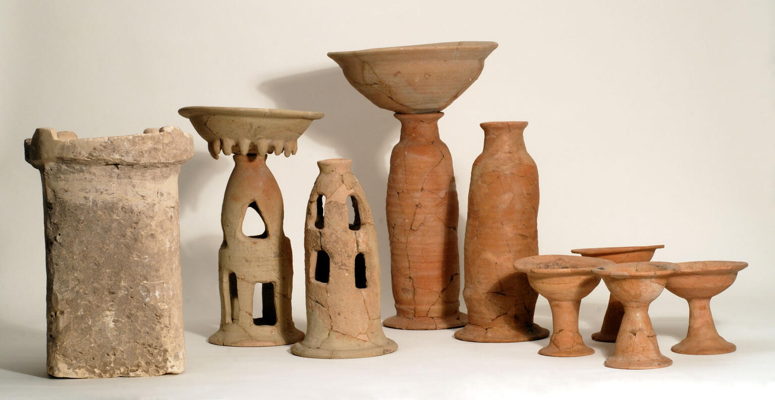 Ritual containers including stone altar, two offering bowls on tall bases, four chalices, and two stands with cylindrical bases.