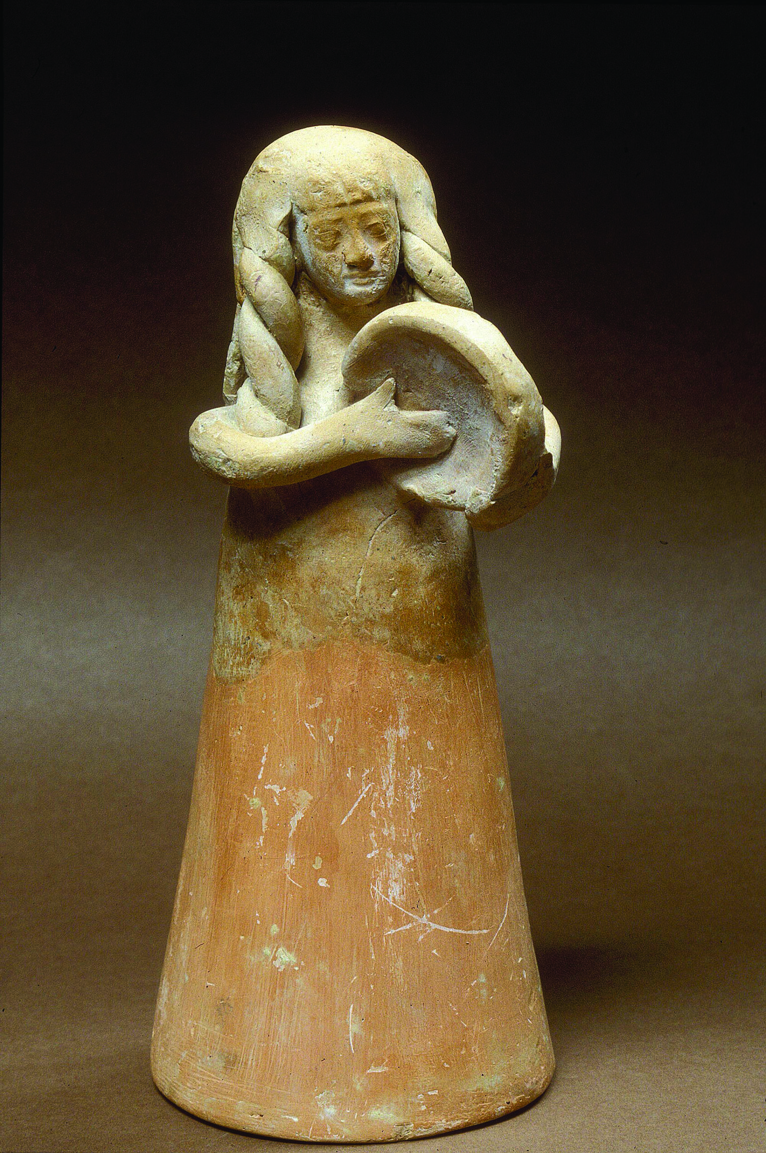 Terra-cotta figurine of women with long hair playing frame drum.