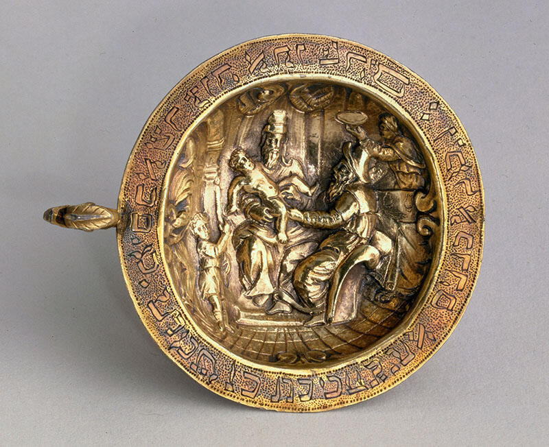 Plate engraved with Hebrew letters around rim and image of man holding child on a chair.