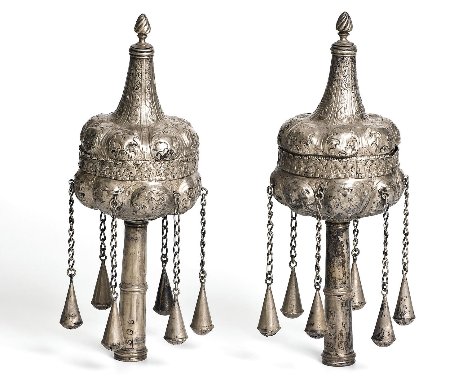Pair of finials with decoration and chains hanging down. Pair of finials with decoration and chains hanging down.