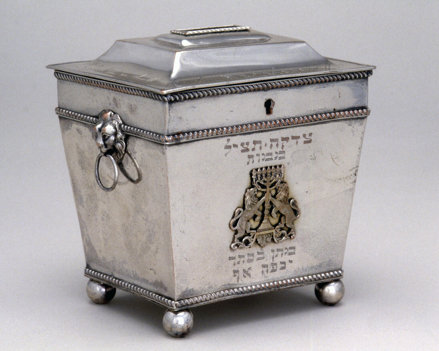 Silver cast and engraved container featuring lions holding menorah. Silver cast and engraved container featuring lions holding menorah.