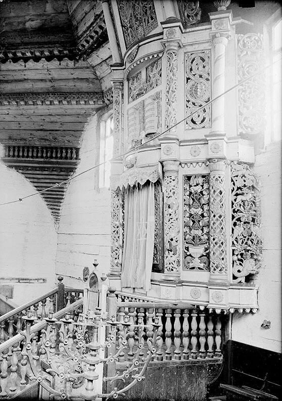 Photograph of interior of building featuring menorah and decorated Torah ark.