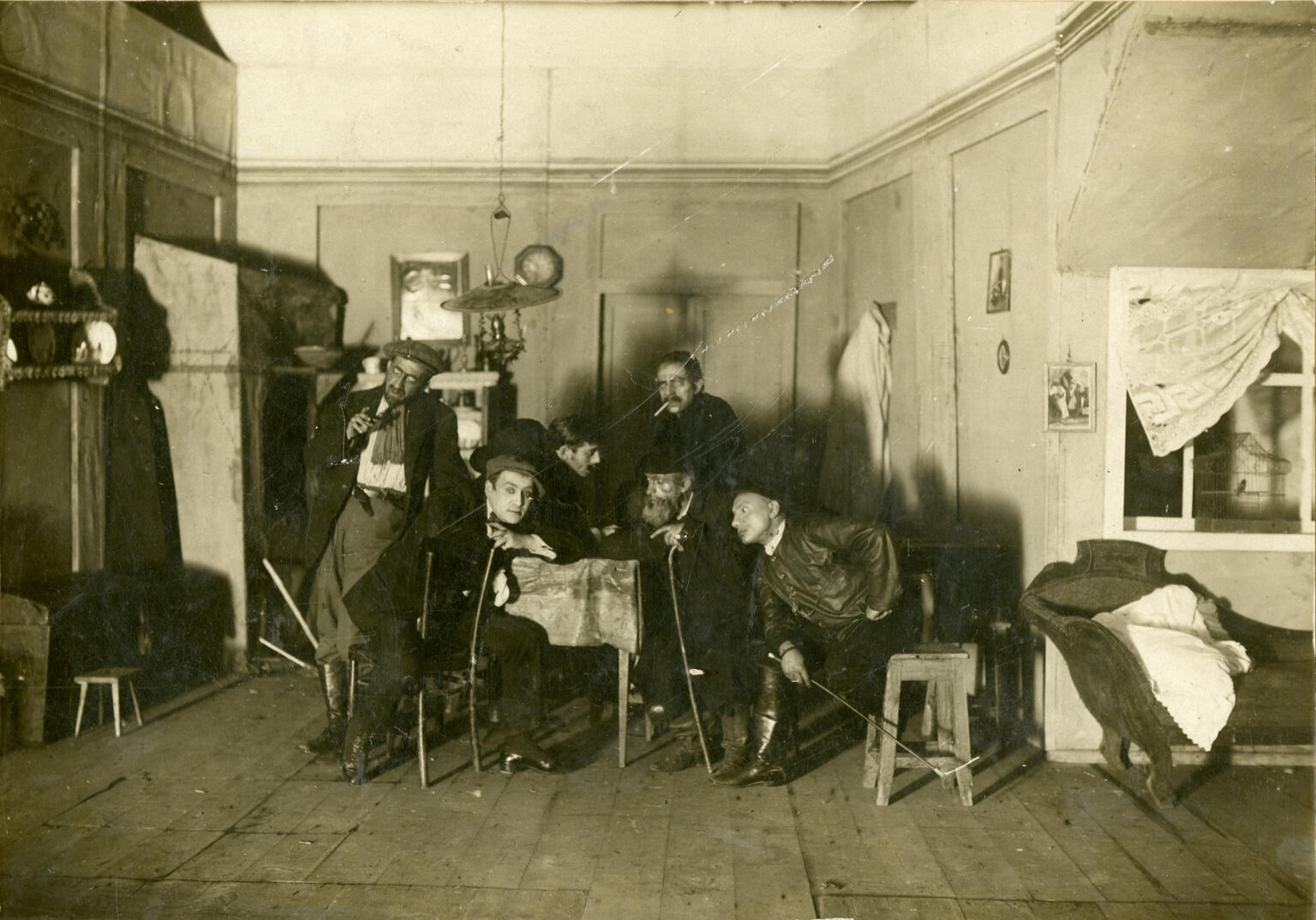 Photograph of figures sitting in furnished room. Photograph of figures sitting in furnished room.