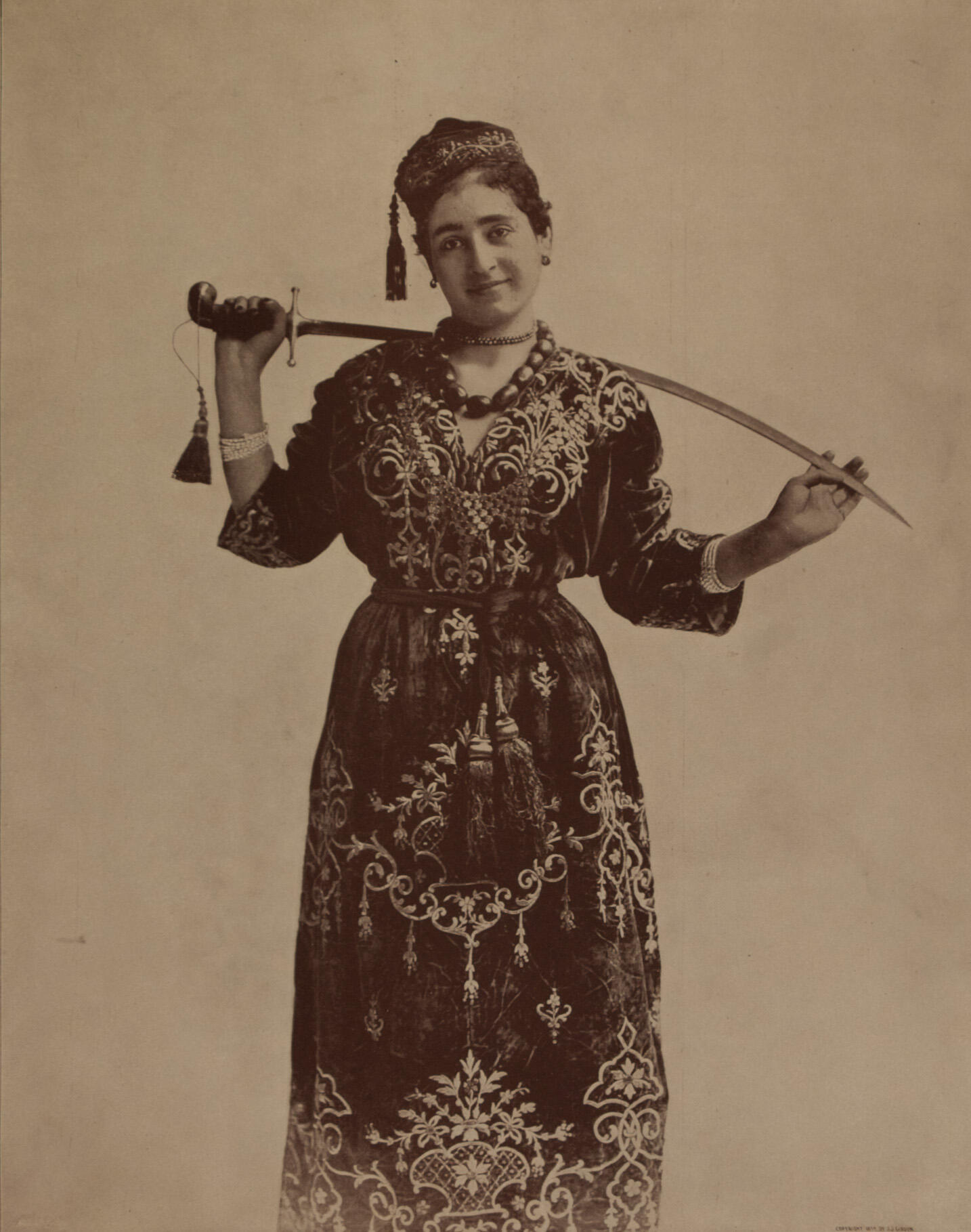 Photograph of figure holding sword behind her neck.