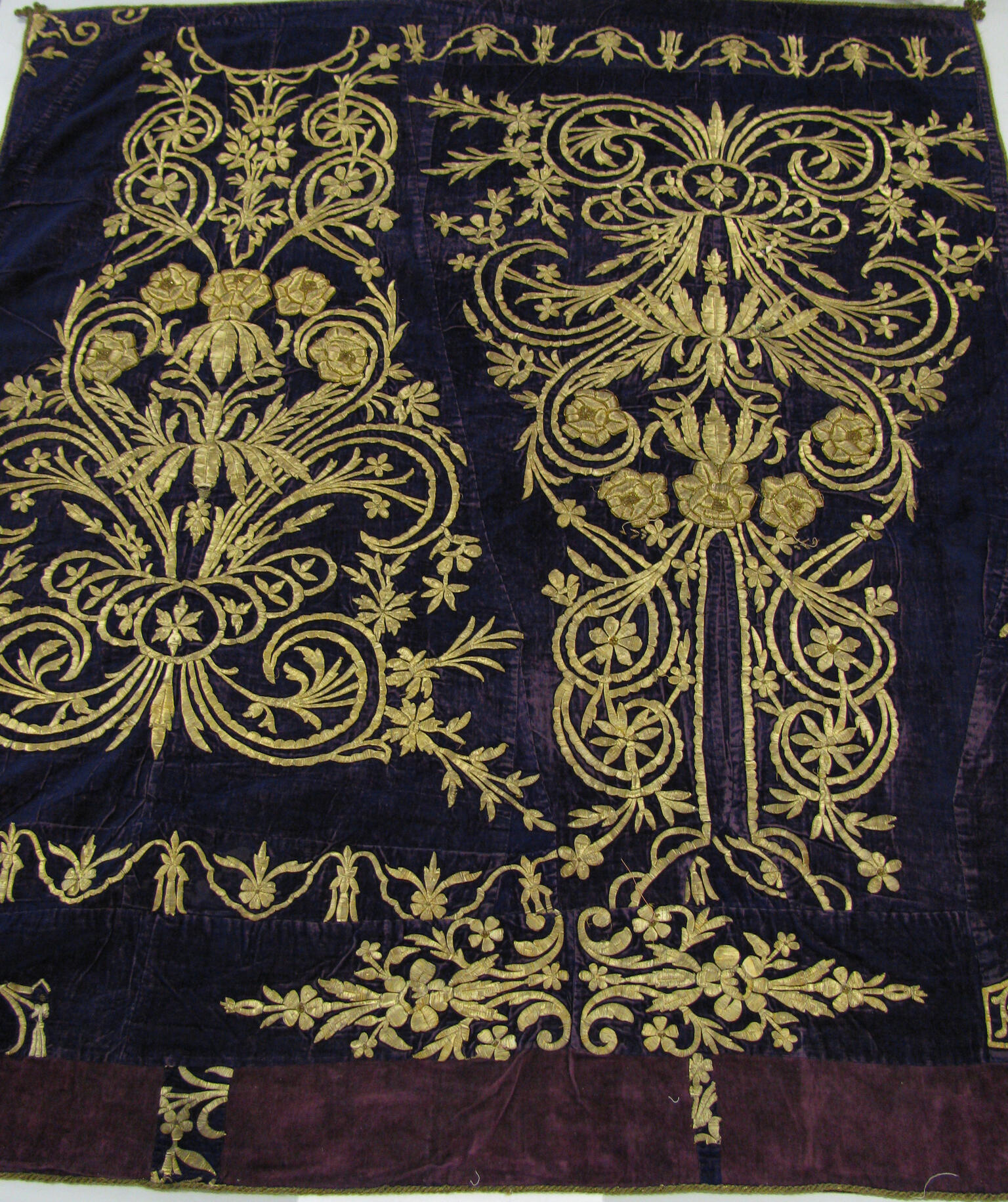 Cloth embroidered with decorative flowers, spirals, and lines.