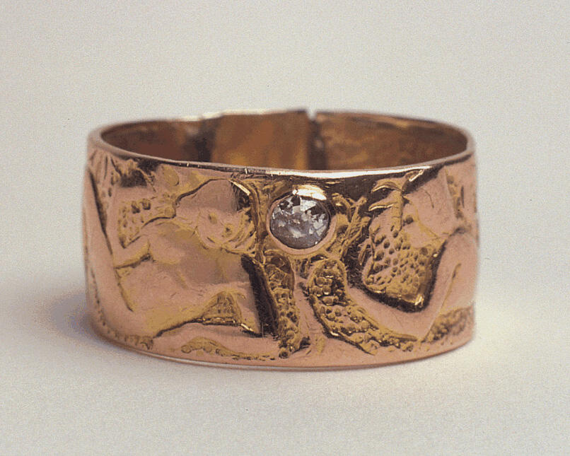 Gold wedding ring stamped with two figures and inlaid with a diamond.