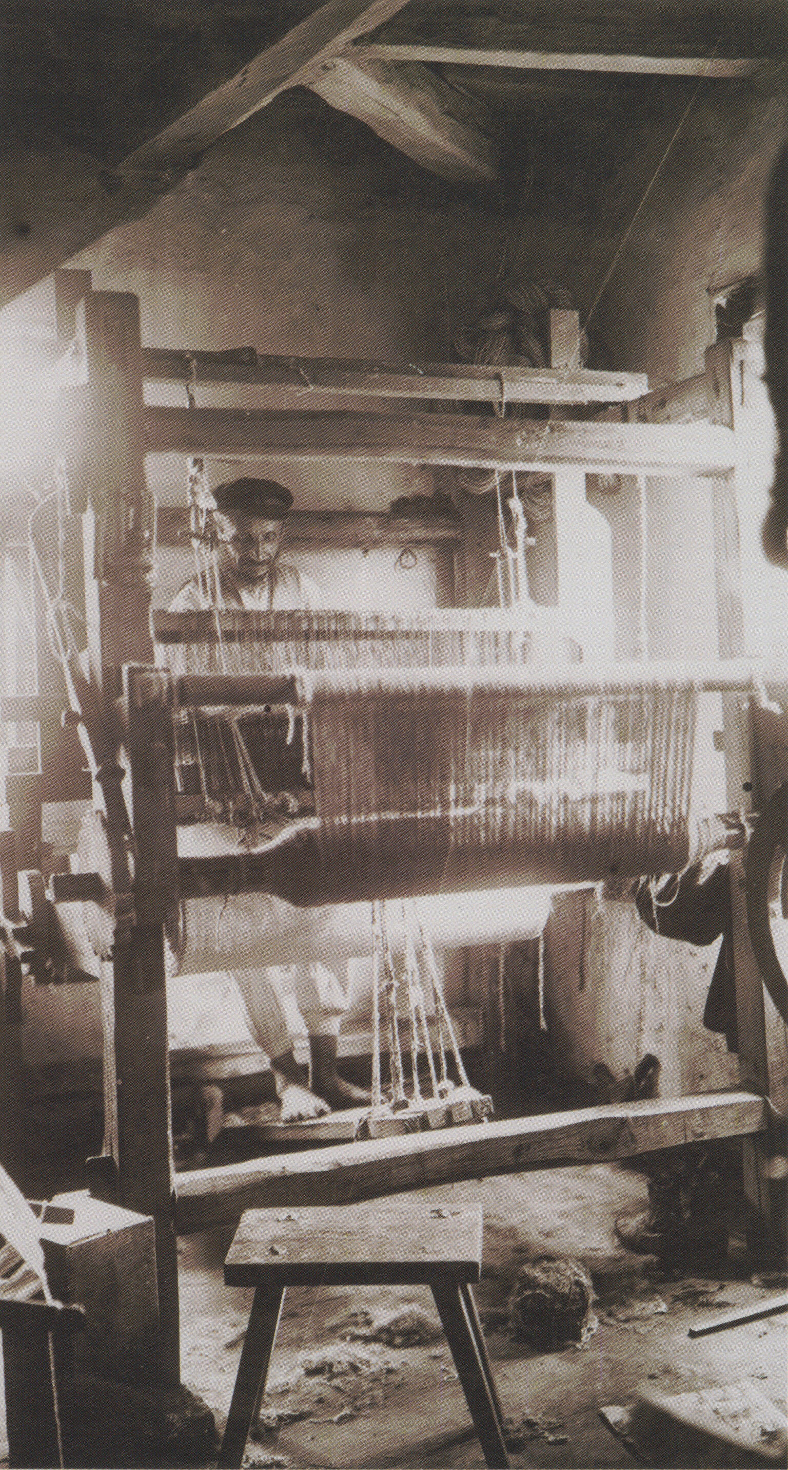 Photograph of large, multilayered loom with figure working on it.