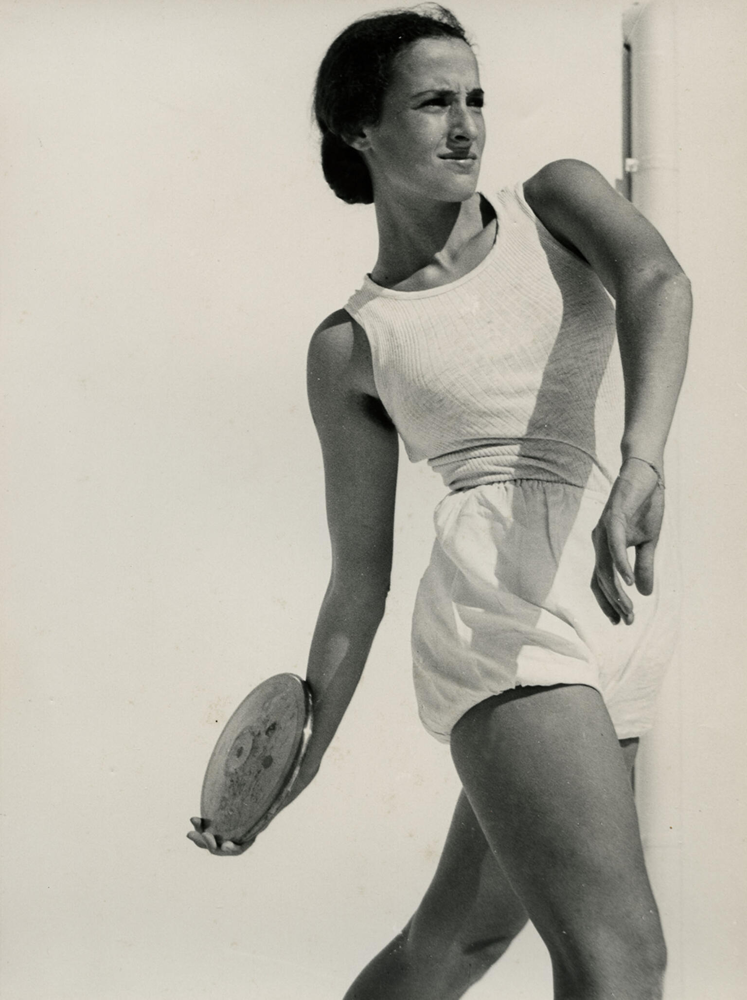 Photograph of female athlete assuming position to throw a discus. Photograph of female athlete assuming position to throw a discus.