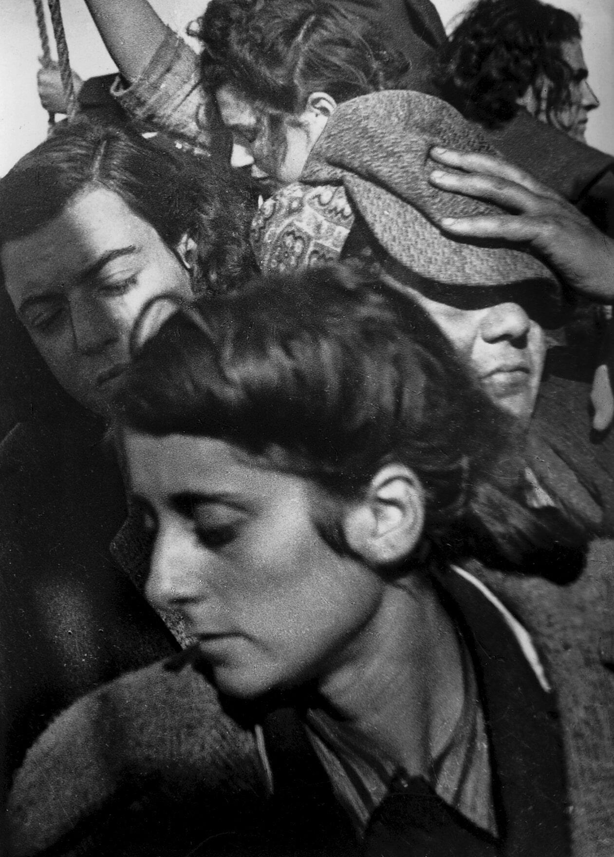 Photograph of female immigrants crowded together, with their faces turned away from viewer.