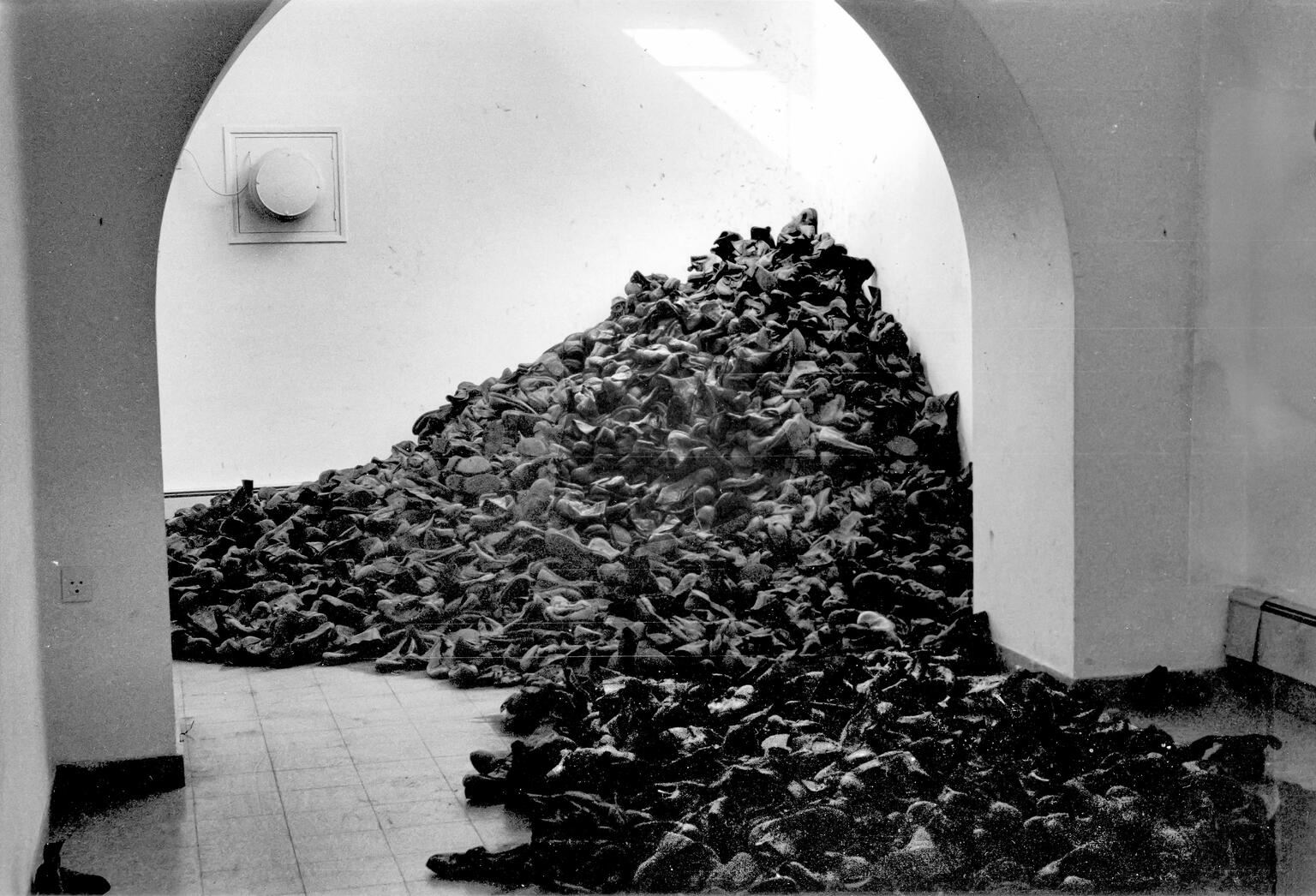 Art installation of large number of boots piled between two rooms. Art installation of large number of boots piled between two rooms.