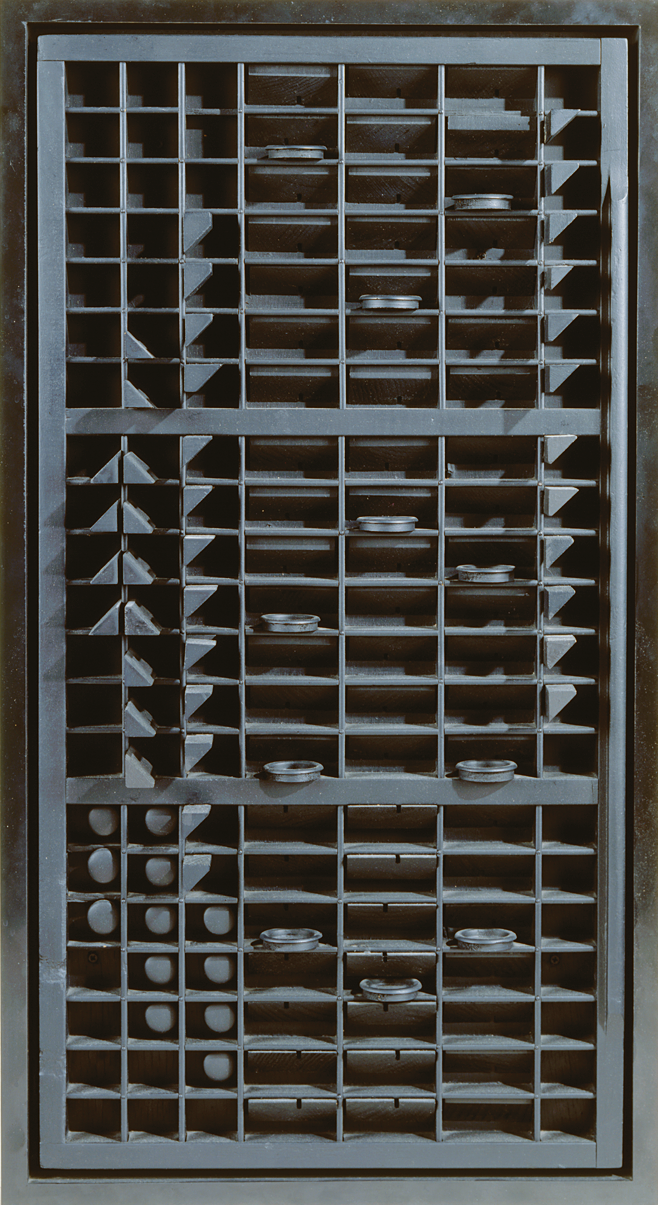 Abstract painted wood sculpture of a rectangle with a grid of small squares and rectangles inside containing triangles and circles.