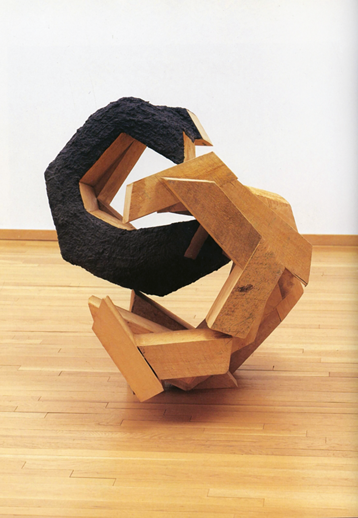 Mixed media on wood sculpture of two interlocked "C" shapes.