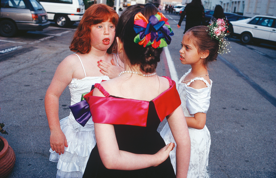 Three young girls wearing party dresses standing in a circle. Three young girls wearing party dresses standing in a circle.